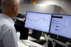 A senior analyst monitors a screen displaying the FTSE 100 index at IG Group in London on April 7, 2025. 