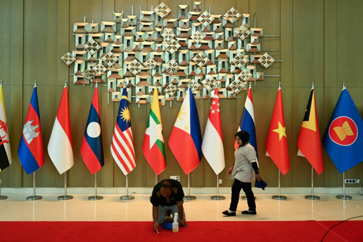 A worker cleans the carpet next to a row of national flags ahead of the ASEAN Foreign Ministers' (AMM) retreat meeting at the Langkawi International Convention Centre on Malaysia's resort island of Langkawi on Jan. 17.