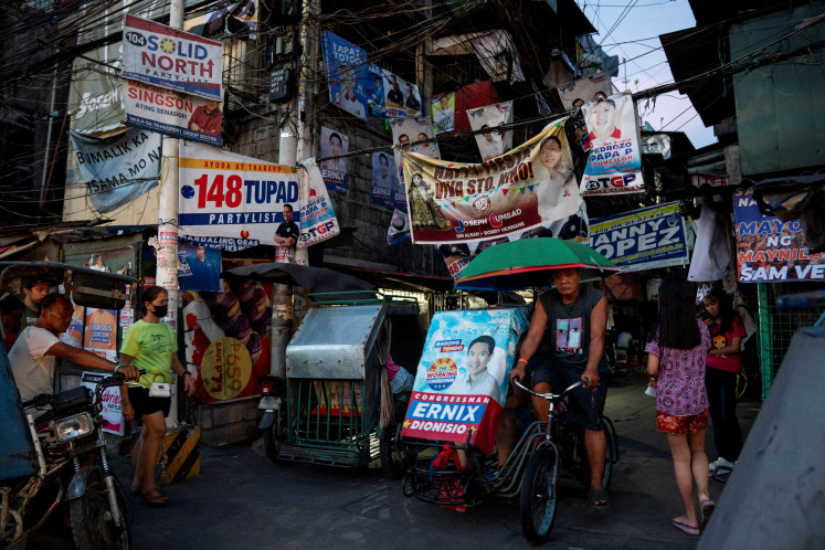 A pedicab driver rides past a street with campaign posters put up, a day before the May 12 midterm elections, in Manila, Philippines, May 11, 2025.