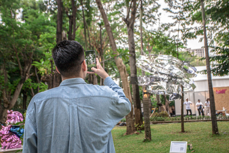 A visitor photographs Kadek Armika’s Circumference’s Light at Art Jakarta Gardens 2025.