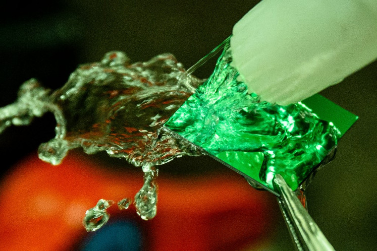 A student washes a semiconductor chip diced from a wafer at the Inter-university Semiconductor Research Center at Seoul National University in Seoul on April 30, 2025.