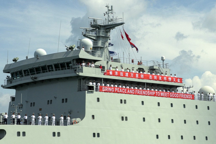 Chinese navy personnel wave near a banner reading “Bring peace and friendship to meet good friends“ on the deck of the training ship Qijiguang as it prepares to dock during a welcome ceremony at the Sihanoukville port in Preah Sihanouk province on May 19, 2024. 