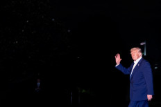 United States President Donald Trump waves while walking across the South Lawn as he returns to the White House following a trip to the Middle East, in Washington on May 16, 2025.