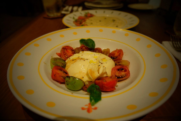 Playful with a sweet twist: House-made burrata with charred tomatoes, basil and grilled grapes.
