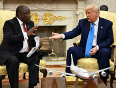 US President Donald Trump hands papers to South African President Cyril Ramaphosa during a meeting in the Oval Office of the White House in Washington, DC, on May 21, 2025. 