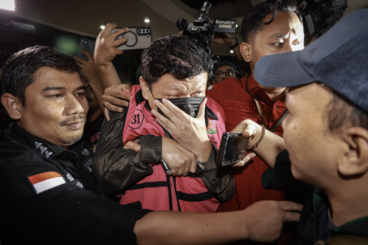 Attorney General's Office (AGO) officers escort Iwan Setiawan Lukminto (center), former president director of textile giant PT Sri Rejeki Isman (Sritex) to a prisoner van after an interrogation session at the AGO building in Jakarta on May 21, 2025. The AGO named him and two other individuals suspects in a corruption case pertaining to the misappropriation of loans disbursed by several banks, including state-owned lenders, that incurred a Rp 692 billion state loss.