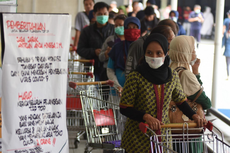 Shoppers queue at a supermarket in Depok, West Java, on Monday. The World Bank has estimated that the COVID-19 pandemic will significantly slow Indonesia’s economic growth this year and may throw millions of people into poverty. 