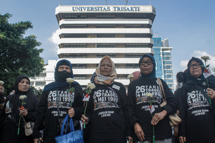 Activists hold flowers on May 17, 2025, during a prayer and vigil for four Trisakti University students who were shot dead during a protest in 1998 at the university's courtyard in Jakarta.