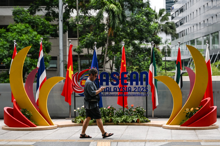 A man walks in front of the logo of ASEAN  on May 25, 2025, ahead of the 46th summit in Kuala Lumpur.