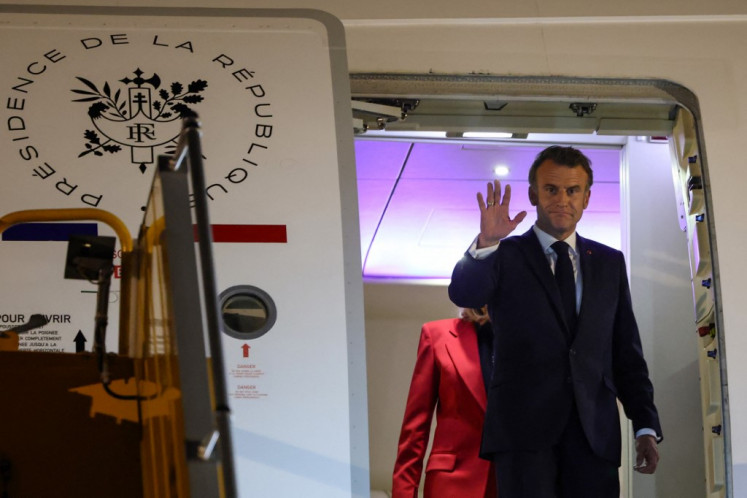 France's President Emmanuel Macron waves in front of his wife Brigitte Macron as they prepare to disembark from the plane upon their arrival at Noi Bai International Airport in Hanoi on May 25, 2025. 