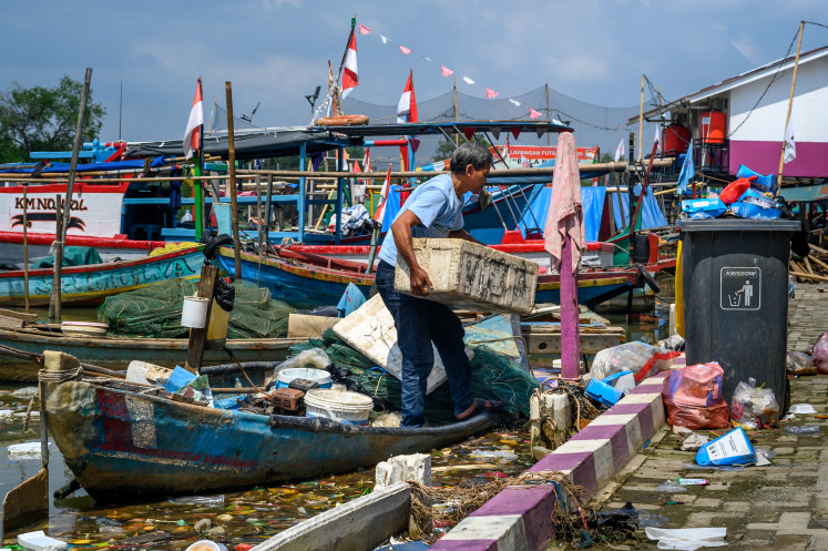 A fisherman unloads his belongings after returning from a fishing trip at the traditional Muara Angke harbor in Jakarta on November 21, 2024. 