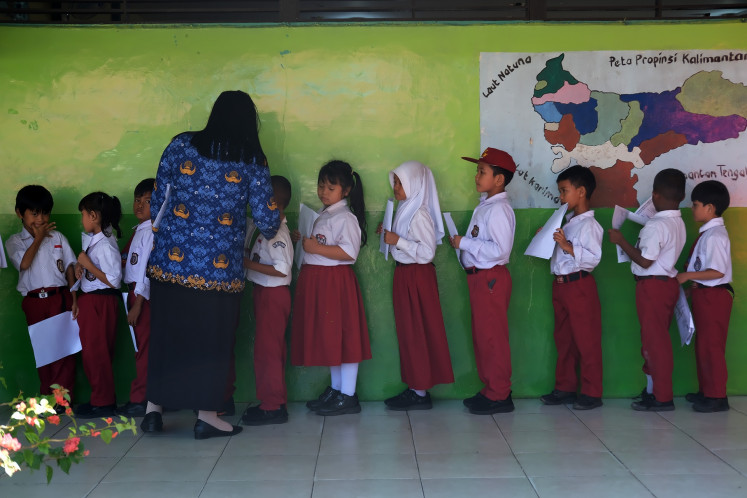 Elementary school pupils hold their civic registry documents while lining up to be photographed by Pontianak Population and Registry Registration Agency at SD 10 state elementary school in Pontianak, West Kalimantan, on May 20, 2025. 