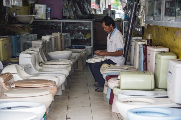 A man works on a toilet bowl seat in a shopping complex specializing in selling secondhand toilet parts in Jakarta on Nov. 14, 2017.