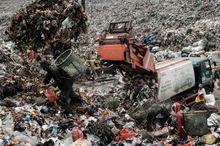 Overwhelming: Registered scavengers, who mainly collect plastic waste to sell, work on Sept. 14, 2023, as a crane moves garbage up to a higher level at the Bantar Gebang landfill in Bekasi, West Java. The landfill, which is the size of 200 soccer pitches and receives 7,500 tonnes of waste from Jakarta every day, has been declared close to capacity.