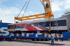 Port workers supervise as an electric railcar being unloaded at Tanjung Priok in North Jakarta on May 30, 2025. Commuter Line operator PT Kereta Commuter Indonesia has ordered eight new trains, 96 cars in all, from China to replace aging units.