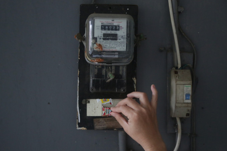 A resident checks an electricity meter in Matraman, Jakarta, on Thursday. Electricity customers in the 450 volt-ampere (VA) category will not be charged for electricity for April, May or June, in an effort to alleviate the economic hardship brought about by the COVID-19 pandemic.