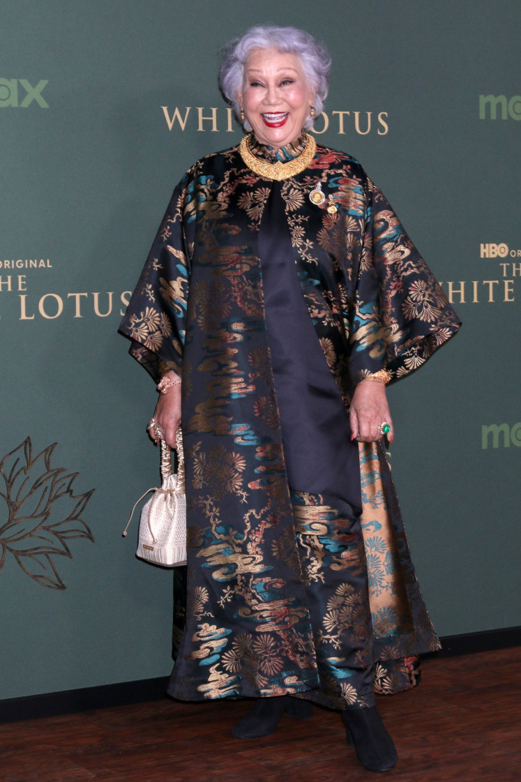 As the eccentric resort owner, Sritala, Patravadi “Lek” Mejudhon brings confidence and poise, though her role rarely moves beyond a polished introduction to her white husband’s larger arc.
