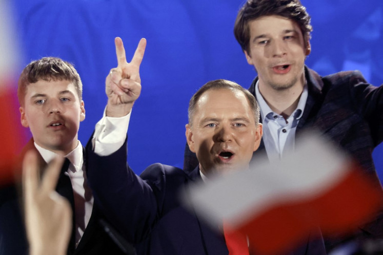 Karol Nawrocki, candidate for the 2025 Polish presidential election supported by Poland's right-wing Law and Justice (PiS) party, flashes the victory sign in front of supporters as exit polls were announced on tv during their election night event at the Mala Warszawa Theatre in Warsaw, Poland, during the second round of the presidential elections on June 1, 2025. T