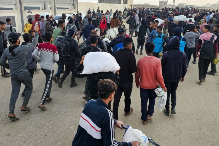 Displaced Palestinians, some carrying sacks of food, leave a distribution centre in Rafah, in the southern Gaza Strip, on June 1, 2025. T