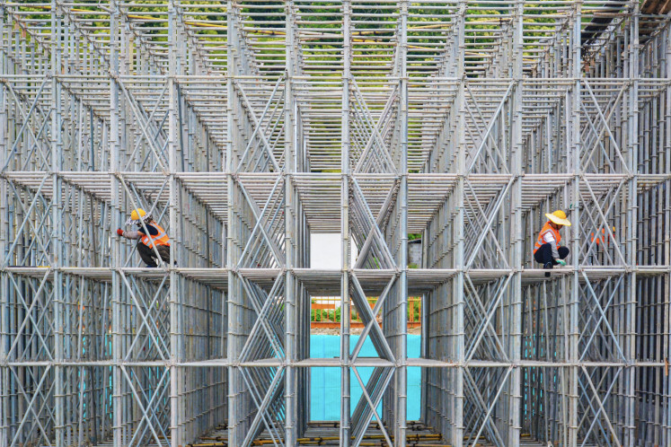Workers are seen on a scaffolding on Monday at the construction site of the Liuqing Railway in Anqing, in eastern China's Anhui province.