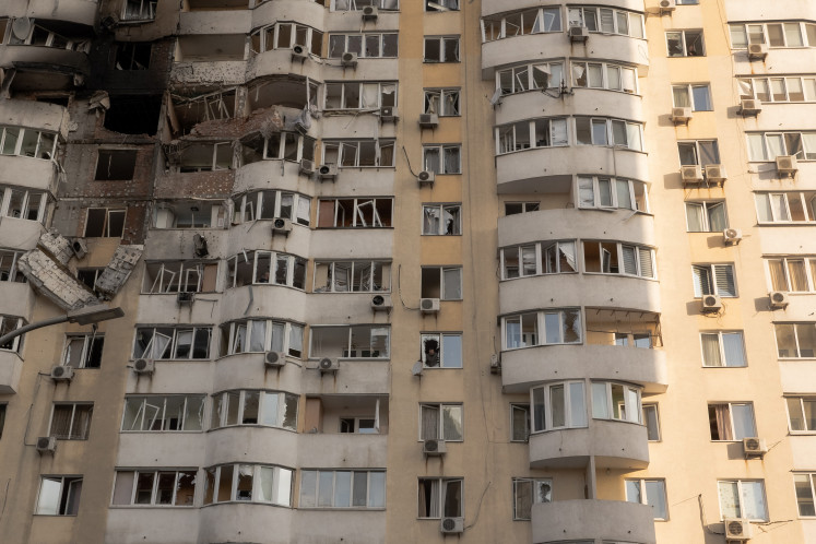 A person looks out from a broken window in a residential building damaged during a Russian air strike in Kyiv on June 6, 2025, amid the Russian invasion of Ukraine. Russia carried out a barrage of drone strikes across Ukraine overnight, killing at least four people and wounding 20 in the capital Kyiv, Ukrainian officials said on June 6.