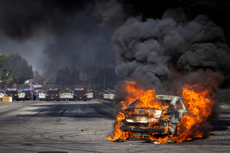 A car burns on Atlantic Boulevard during a standoff by protesters and law enforcement, following multiple detentions by Immigration and Customs Enforcement (ICE), in the Los Angeles County city of Paramount, California, US on June 7, 2025. 