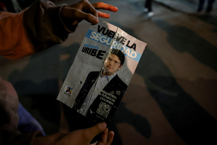 A person holds a campaign poster at the area where Colombian Senator Miguel Uribe Turbay of the opposition Democratic Center party, was shot during a campaign event, in Bogota, Colombia, on June 7, 2025.