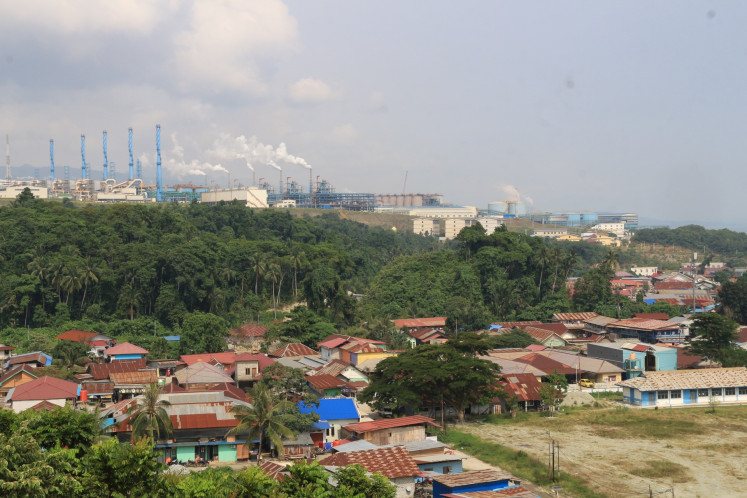 Smoking barrels: A nickel smelting and processing site operated by PT Indonesia Weda Bay Industrial Park (IWIP) is seen on Feb. 20 in the background of the Lelilef Sawai village in Central Weda district, Central Halmahera regency, North Maluku. Residents have complained about pollution from the industrial park that has caused people to fall sick.