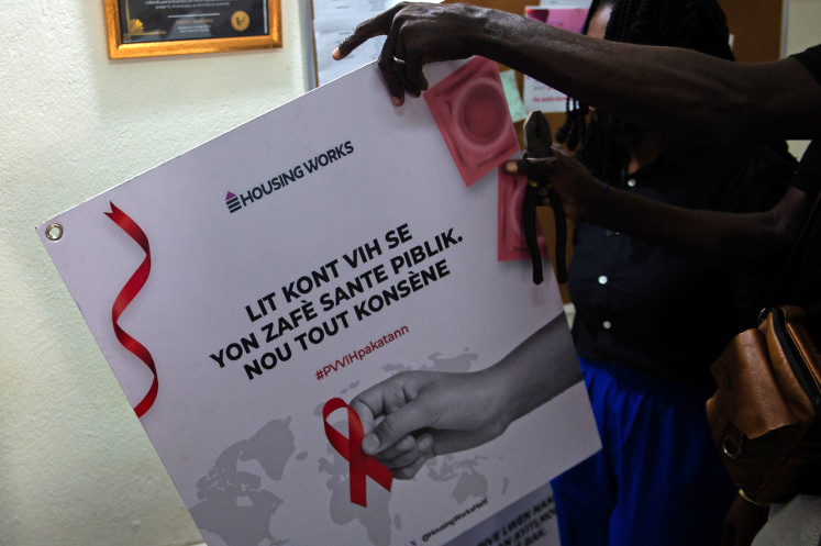A man holds a placard that reads “The fight against HIV is a public matter. Everyone is concerned” from Housing Works, a charity that helps Haitians living with HIV/AIDS, for displaying on June 2, 2025, at an office in Port-au-Prince.