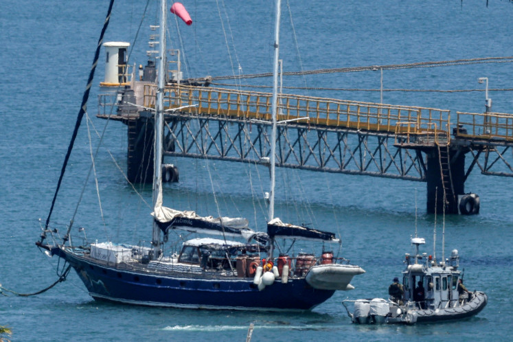 An Israeli police patrol boat moves near the aid sailboat Madleen as it is moored at the southern port of Ashdod on June 10, 2025 after being intercepted the previous day by Israeli forces. Israeli forces intercepted the Gaza-bound aid boat Madleen, operated by the Freedom Flotilla Coalition activist group, on June 9, preventing the activists on board from reaching the blockaded Palestinian territory.