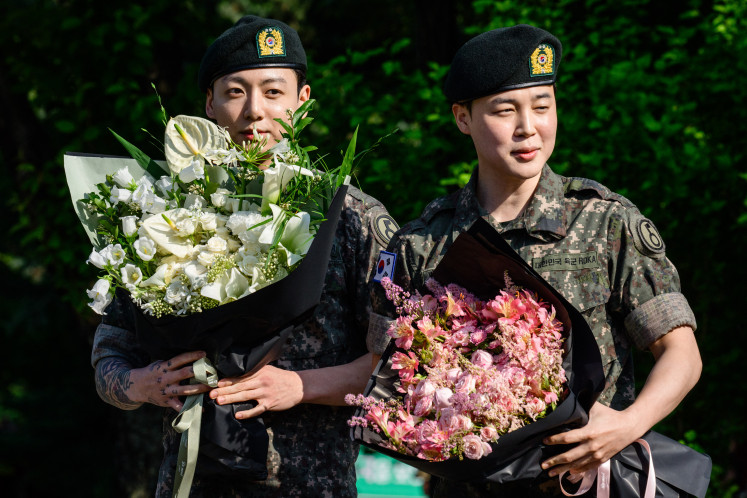 Jungkook (left) and Jimin of K-pop supergroup BTS hold bouquets of flowers at an outdoor sporting facility in Yeoncheon on June 11, 2025, shortly after their release from 18 months of South Korean military service.
