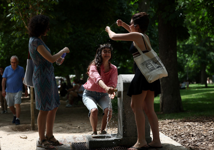 Women refresh in a fountain during a hot day at Retiro Park, in Madrid, Spain on June 1, 2025.