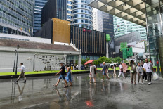 People walk outside office buildings during lunchtime in the financial district of Raffles Place in Singapore on May 22, 2025.