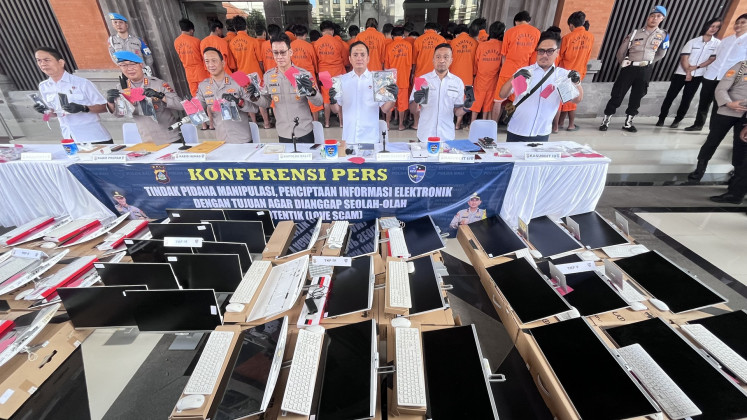 Bali Police chief Insp. Gen. Daniel Adityajaya (center) holds pieces of evidence during a press briefing about an alleged love scam at police headquarters in Denpasar, Bali, on June 11.