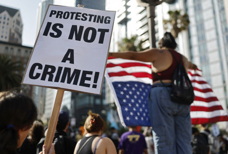A person holds a “Protesting Is Not A Crime!“ sign as people demonstrate before marching downtown as protests against ICE immigration raids continue in the city on June 11, 2025 in Los Angeles, California, US. Tensions in the city remain high with daily protests after the Trump administration called in the National Guard and the Marines against the wishes of Governor Gavin Newsom and city leaders. 
