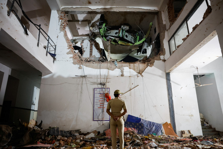 A police officer stands in front of the wreckage of an Air India aircraft, bound for London's Gatwick Airport, which crashed during take-off from an airport in Ahmedabad, India June 12, 2025.