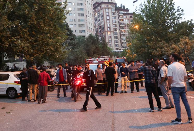 People gather in the street in the aftermath of Israeli strikes, in Tehran on June 13, 2025.