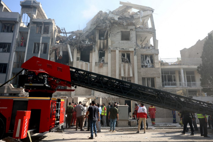 Rescue teams work outside a heavily damaged building, targeted by an Israeli strike in the Iranian capital Tehran on June 13, 2025. Israel carried out strikes against Iran early on June 13, targeting its nuclear and military sites as well as residential buildings in Tehran, after US President Donald Trump warned of a possible “massive conflict“ in the region. 