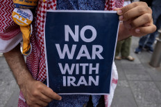 A demonstrator holds an anti-war sign during a protest against Israeli strikes on Iran, in New York City, US, June 13, 2025. 