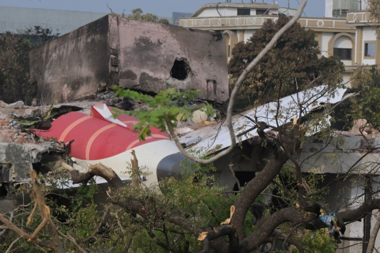 The tail section of Air India flight AI171 is suspended atop a residential building on June 14, 2025, near Sardar Vallabhbhai Patel International Airport in Ahmedabad, Gujarat state, India. Investigators recovered the flight data recorder, one of two “black boxes”, from the wreckage of the London-bound Boeing 787-8 on June 13, the day after the commercial jet crashed shortly after takeoff, killing at least 279 people on board and on the ground.