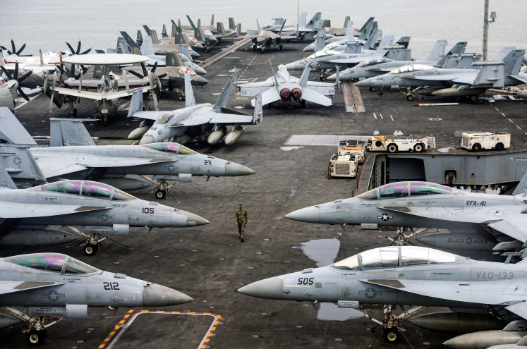 A US Navy officer walks past fighter jets parked on the flight deck of the Nimitz-class aircraft carrier USS Abraham during a media tour in Port Klang, on the outskirts of Kuala Lumpur, on November 26, 2024. 