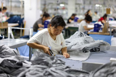 An employee uses a pair of scissors to trim clothes for export at a clothing factory in Tongren, in southwestern China's Guizhou province, on May 15, 2025.