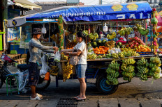 A woman buys fruit along a street in Phnom Penh on March 14, 2024.