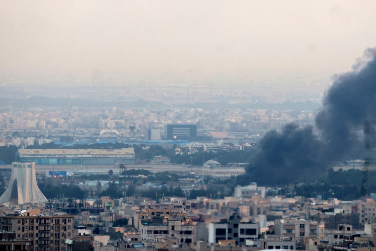Smoke billows from a site near the Azadi Tower (left) in central Tehran, as fighting between Israel and Iran continues on June 16, 2025.