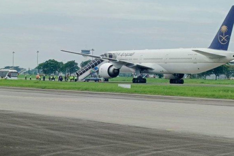 Airport authorities observe as a Saudia Airlines' Boeing 777-300ER is parked at an isolated position at Kualanamu International Airport outside Medan, North Sumatra, on June 17, 2025. The aircraft was flying 442 haj pilgrims from Jeddah, Saudi Arabia, to Jakarta when it diverted to Kualanamu airport after receiving a bomb threat.