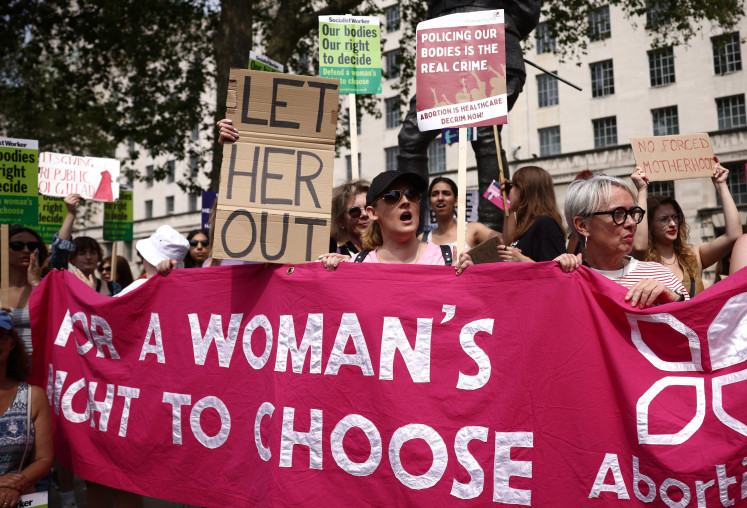 Protesters hold up placards during a march through central London on June 17, 2023, to call for decriminalization of abortion.
