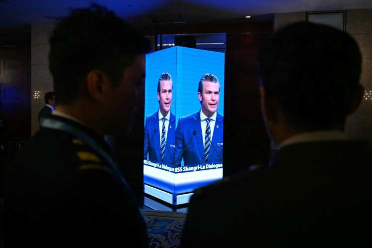 Attendees outside the ballroom watch on a screen as United States Secretary of Defense Pete Hegseth delivers an address at the Shangri-La Dialogue Summit in Singapore on May 31.