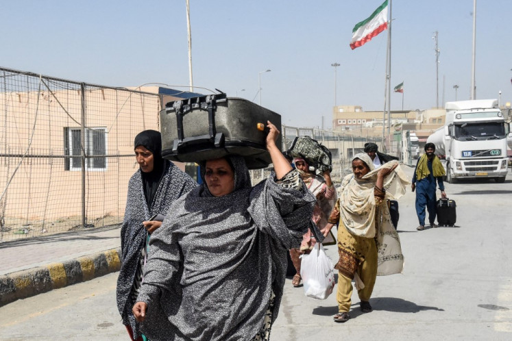Pakistani Shiite pilgrims carry their belongings across the Pakistan-Iran border after returning from Iran in Taftan, in Balochistan province, on June 19, amid the ongoing conflict between Israel and Iran.