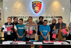 Bogus job recruiters: Two suspects allegedly involved in a human trafficking ring (second left and second right, front row) are displayed on Thursday while the Central Java Police's General Crimes Directorate chief Sr. Comr. Dwi Subagio (left) and chief spokesman Sr. Comr. Artanto (center) hold envelopes of evidence in Semarang, Central Java. 