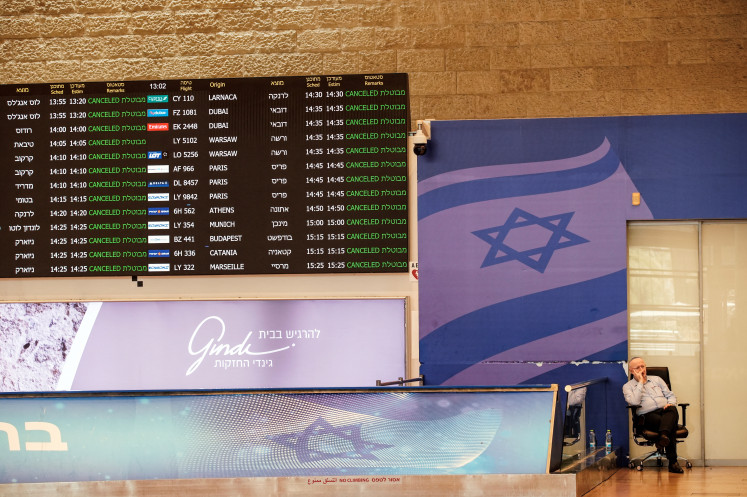 A staffer of Ben Gurion International Airport sits at the arrivals terminal as all flights from and to the airport are cancel.